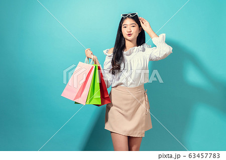 Young smiling asian woman holding multi coloured shopping bags and hands touch the glasses. 63457783