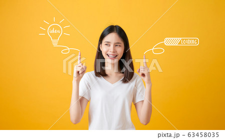 Young smiling Asian woman pointing hands to light bulb with text ideas and loading brainstorm. Young smiling Asian woman pointing hands to light bulb with text ideas and loading brainstorm. 63458035