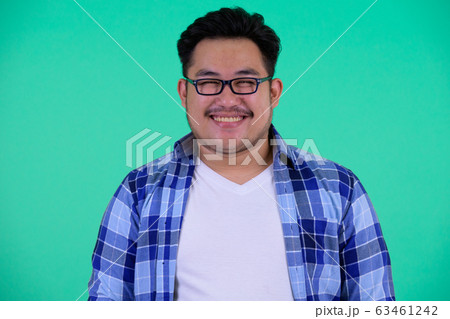 Face of happy young overweight Asian hipster man smiling Face of happy young overweight Asian hipster man smiling 63461242