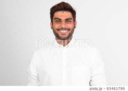 Happy young bearded Indian man smiling against white background 63461790