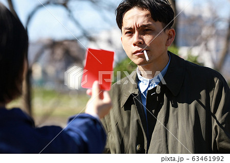 レッドカードを出される歩きタバコの男性 63461992