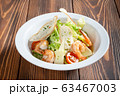 Plate of caesar salad with prawns on wooden table 63467003