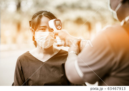 The eyes of fear on Asian woman face who is being measured using a digital fever meter by government officials during the Coronavirus disease 2019 (COVID-19) epidemic. 63467913