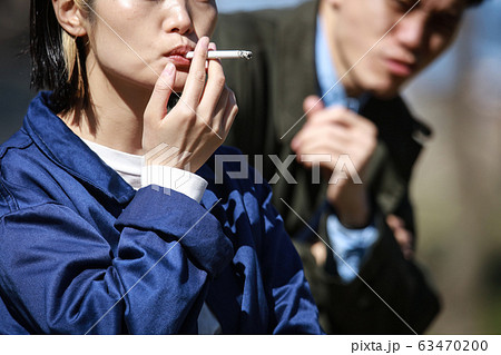 タバコを吸う女性と嫌がる男性の写真素材