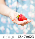 A woman holding a strawberry in her hand 63470623