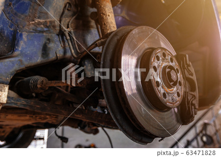Car brake disc closeup on car service lifted for Car brake disc closeup on car service lifted for 63471828