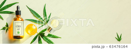 Glass brown bottle with cannabis CBD oil with label and hemp leaves on a marble background. Copy space 63476164