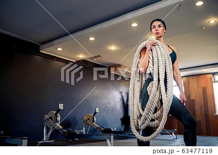 Caucasian fit woman dressed in sportsoutfit posing with battle ropes at gym Caucasian fit woman dressed in sportsoutfit posing with battle ropes at gym 63477119