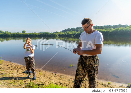 Father and son fishing on the lake together. Father and son fishing on the lake together. 63477592