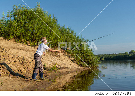 Photo of a young boy fishing outdoors on a summer day. 63477593