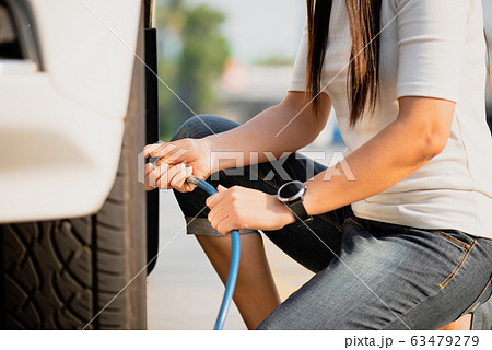 Woman driver checking air pressure and filling air 63479279