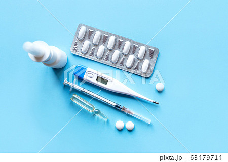 Digital thermometer and medicaments on blue background. Digital thermometer and medicaments on blue background. 63479714