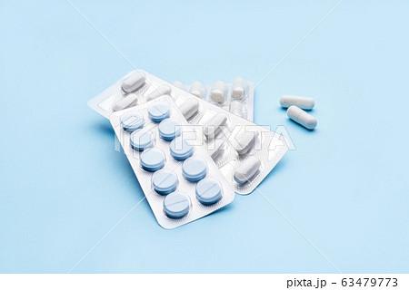 Pills in blister packs on blue background. 63479773