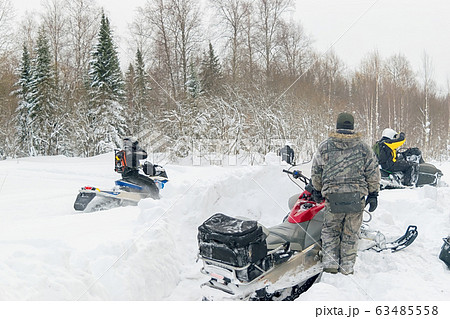 athletes on snowmobiles ride through snowdrifts on a snowy road 63485558