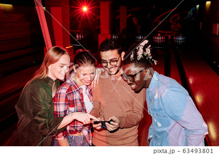 Group of happy young intercultural friends scrolling through their photos 63493801