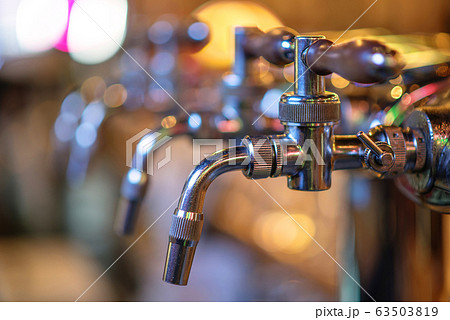 glass of beer in pub, hand of bartender pouring a large lager beer in tap, the beer taps in a pub 63503819