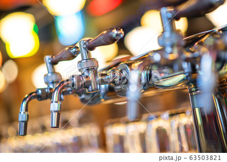 glass of beer in pub, hand of bartender pouring a large lager beer in tap, the beer taps in a pub 63503821