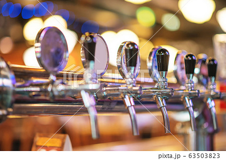 glass of beer in pub, hand of bartender pouring a large lager beer in tap, the beer taps in a pub glass of beer in pub, hand of bartender pouring a large lager beer in tap, the beer taps in a pub 63503823