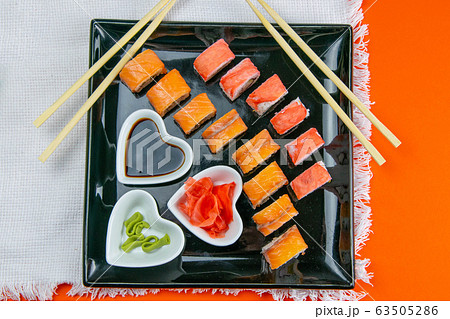 Black plate with sushi, filled with rolls of 63505286