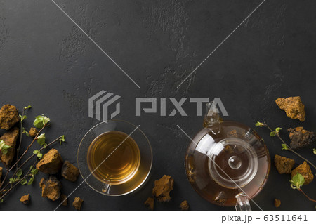 Chaga beverage in glass cup and teapot on black. 63511641
