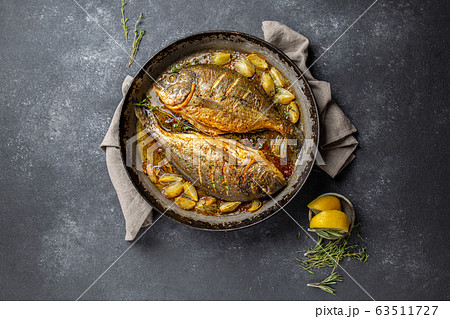 Baked sea bream or dorada with onion and herbs in pan on dark background 63511727