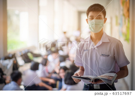 The Asian high school students in the white school uniforms wearing the masks to reading the books to prepare final exams in the midst of Coronavirus disease 2019 (COVID-19) epidemic. The Asian high school students in the white school uniforms wearing the masks to reading the books to prepare final exams in the midst of Coronavirus disease 2019 (COVID-19) epidemic. 63517697