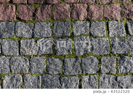 Paving stones made of natural stone. Paths for pedestrians. Beautiful square-shaped stones. Grass breaks through the rocks. The view from the top. Paving stones made of natural stone. Paths for pedestrians. Beautiful square-shaped stones. Grass breaks through the rocks. The view from the top. 63522320