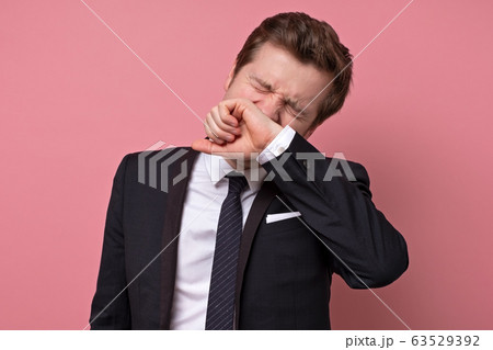 Handsome young man sneezing, isolated on pink 63529392