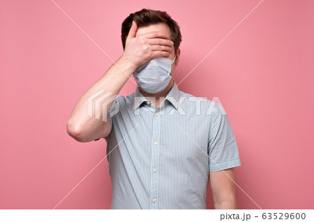 man in medical mask and covering eyes with hand. man in medical mask and covering eyes with hand. 63529600