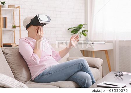 Amazed senior woman enjoying realism of VR at home 63530076