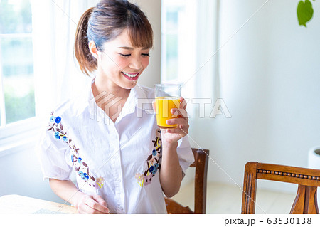 窓際でオレンジジュースを飲む女性 63530138
