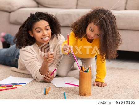 Black Mother And Little Daughter Sketching Lying On Floor Indoors Black Mother And Little Daughter Sketching Lying On Floor Indoors 63530155