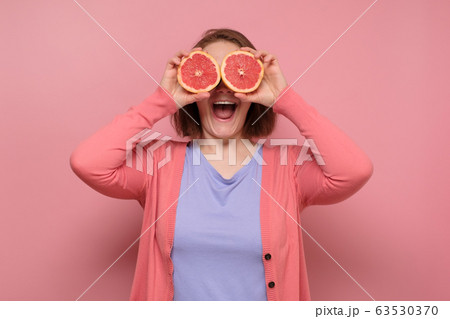 Lovely girl holding a slice of grapefruit in front 63530370