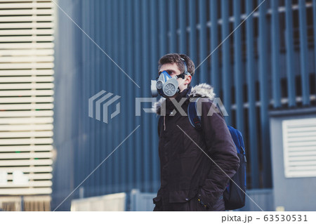 man with backpack wearing industrial mask in city. 63530531