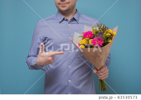 Unrecognizable man in blue shirt holding flowers Unrecognizable man in blue shirt holding flowers 63530573