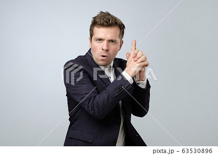 Young businessman doing a gun gesture getting 63530896