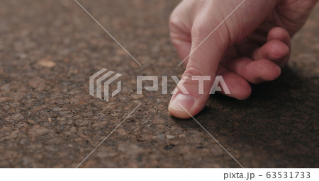 man hand touch dark cork surface with oil finish 63531733