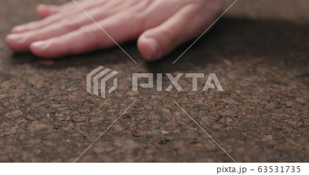 man hand touch dark cork surface with oil finish 63531735