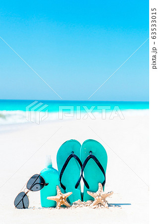 Suncream bottles, goggles, starfish and sunglasses on white sand beach background ocean 63533015