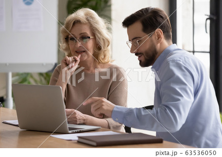 Focused diverse colleagues cooperating at meeting in office 63536050