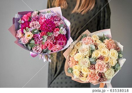 Two Beautiful bouquets of mixed flowers in womans hands. Work of the florist at a flower shop. Delivery fresh cut flower. European floral shop. 63538018
