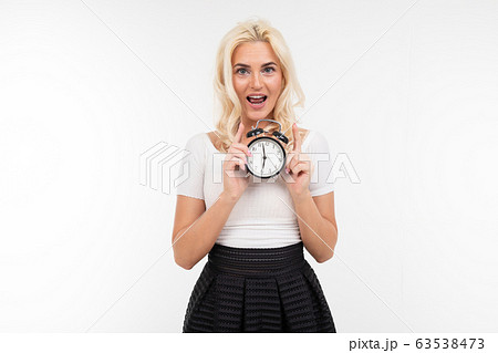 blond girl in a white t-shirt holds an alarm clock on a white background with copy space blond girl in a white t-shirt holds an alarm clock on a white background with copy space 63538473