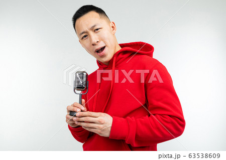 brunette guy in a red sweater sings into a retro microphone on a white background brunette guy in a red sweater sings into a retro microphone on a white background 63538609