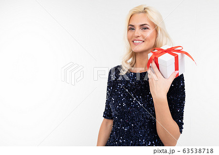 blond Caucasian woman in a blue shiny dress joyfully holds a received gift box on a white background blond Caucasian woman in a blue shiny dress joyfully holds a received gift box on a white background 63538718