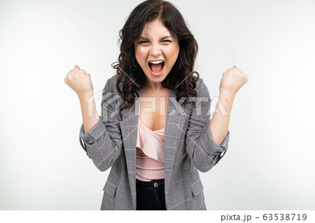 joyful girl in a classic gray jacket is jumping with happiness on a white background joyful girl in a classic gray jacket is jumping with happiness on a white background 63538719