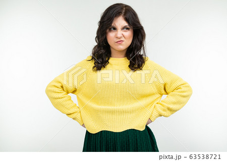 dissatisfied girl in a yellow sweater and green skirt on a white background dissatisfied girl in a yellow sweater and green skirt on a white background 63538721