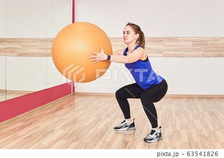 young woman is training by doing squats with fyt young woman is training by doing squats with fyt 63541826