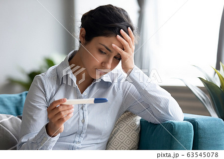 Unhappy Indian woman looking at pregnancy test, upset by result Unhappy Indian woman looking at pregnancy test, upset by result 63545078