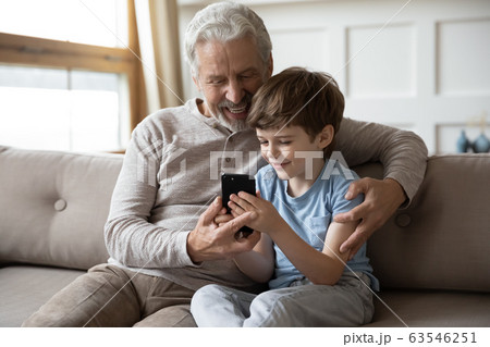 Smiling elderly grandfather and little grandson using smartphone together Smiling elderly grandfather and little grandson using smartphone together 63546251
