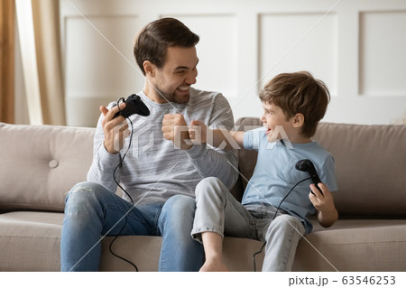 Overjoyed young dad and little son play video games together 63546253